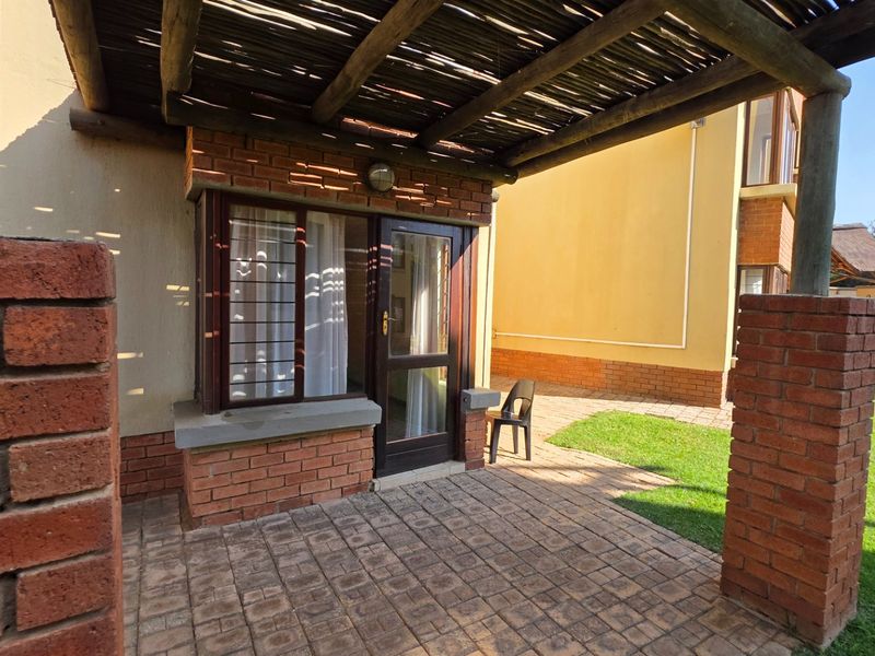 A covered patio area featuring brick pillars, a timber pergola, and paved flooring, providing direct access to the garden.