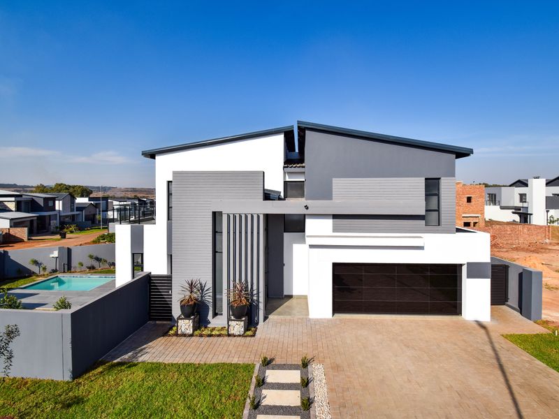 Modern double-story residential home featuring a contemporary facade, paved driveway, integrated double garage, and a private swimming pool.