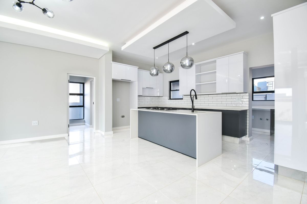 Modern, open-plan kitchen featuring a central island, sleek white and grey cabinetry, subway tile backsplash, and high-quality porcelain floor tiles.
