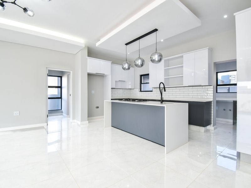 Modern, open-plan kitchen featuring a central island, sleek white and grey cabinetry, subway tile backsplash, and high-quality porcelain floor tiles.