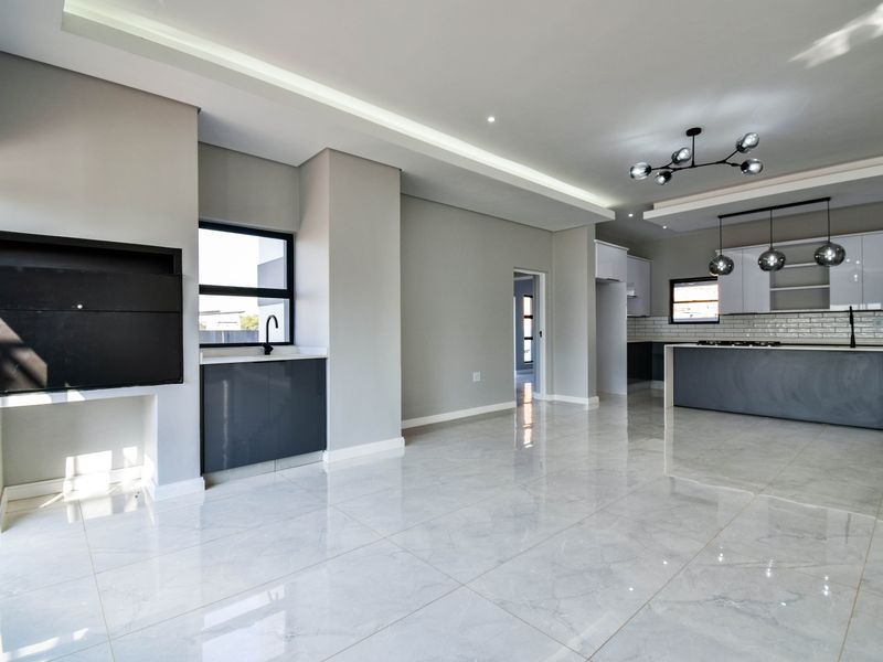Modern open-plan living and kitchen area featuring high-gloss cabinetry, a central island with gas hob, built-in fireplace, and polished porcelain floor tiles.