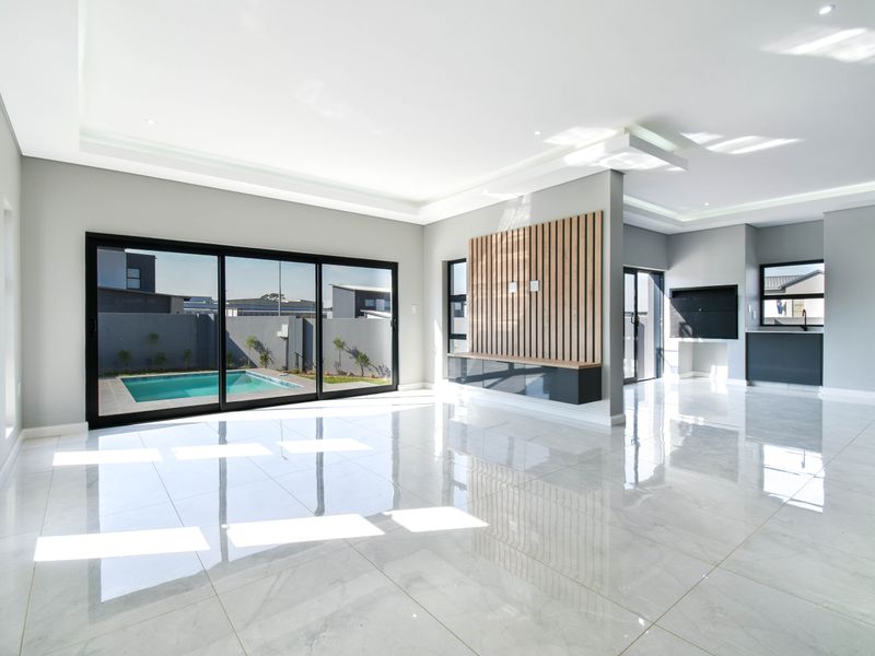 Spacious open-plan living area featuring polished porcelain tiles, recessed lighting, a modern timber slat media wall, and sliding doors opening to the pool area.