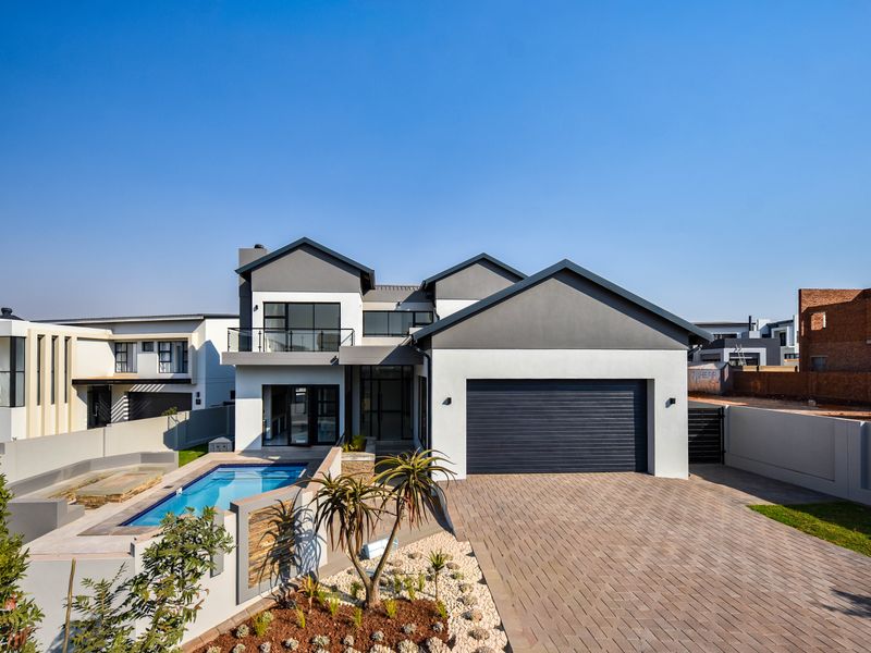 Modern double-story residence featuring a paved driveway, integrated double garage, and a private swimming pool with landscaped garden area.