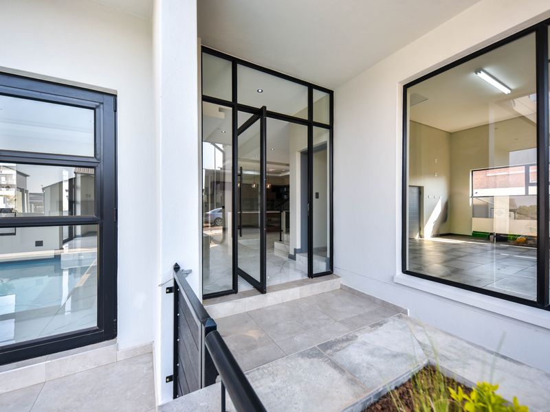 Modern entrance area featuring large format floor tiles and sleek black aluminium framed glass doors and windows, providing a bright and contemporary welcome.