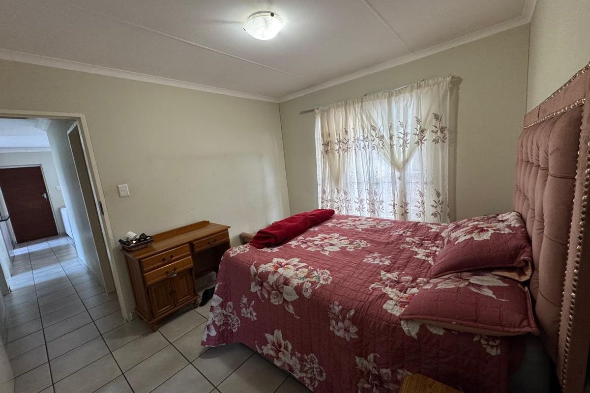 A functional bedroom featuring tiled flooring, coved ceilings, and a central light fixture, offering a neutral base for potential interior updates.