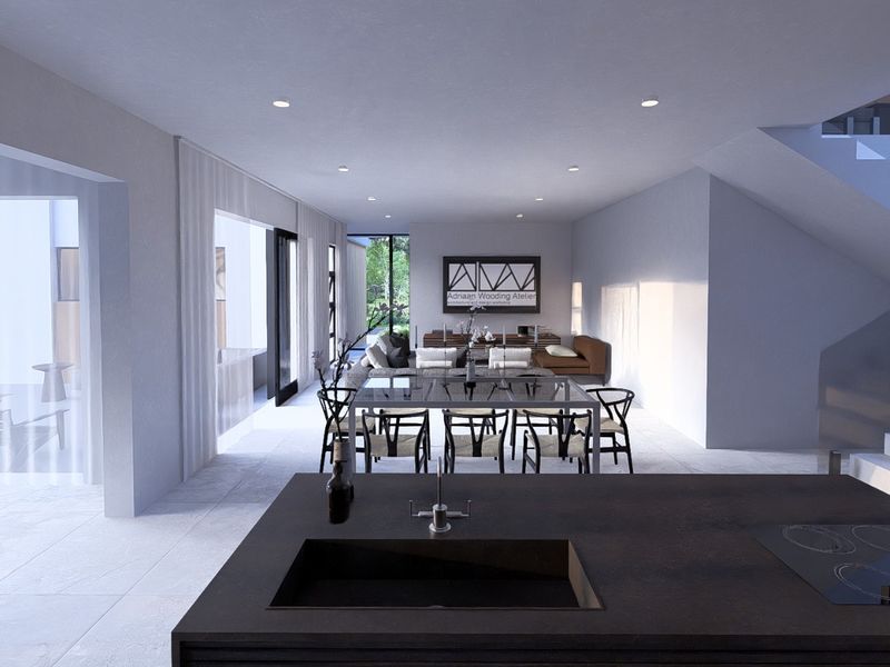 Spacious open-plan living and dining area featuring a modern kitchen island with integrated cooktop and sink, flowing seamlessly to an outdoor patio space.