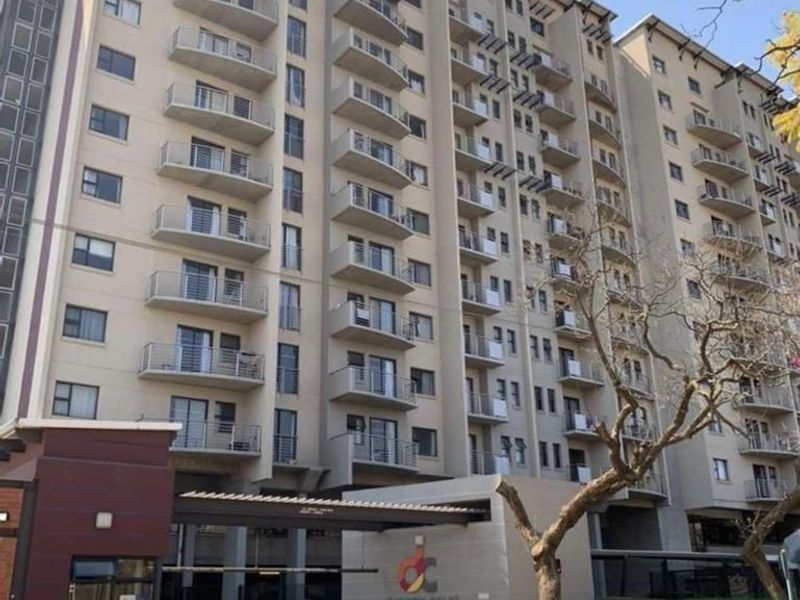 Exterior view of Duncan Court apartment building featuring a secure gated entrance, paved driveway, and multiple levels of private balconies.