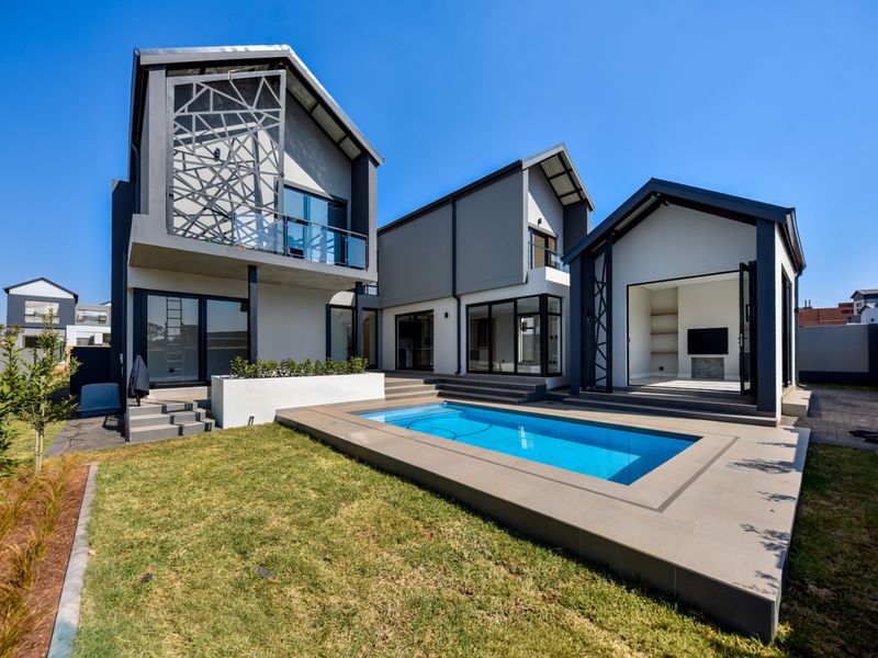 Modern rear exterior view featuring a swimming pool, tiled patio area, and contemporary architectural design with large glass sliding doors.