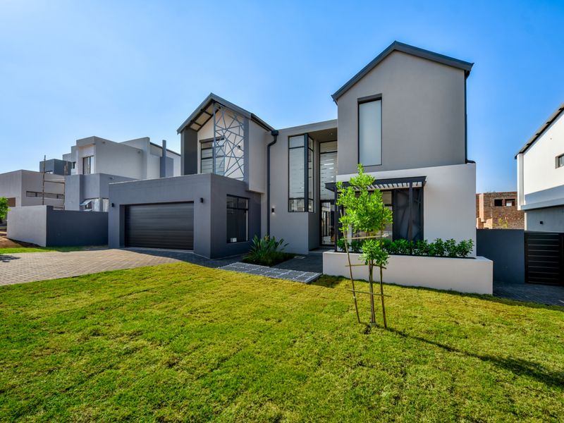 A modern double-story residential home featuring a contemporary facade, paved driveway, double garage, and a well-maintained front lawn.