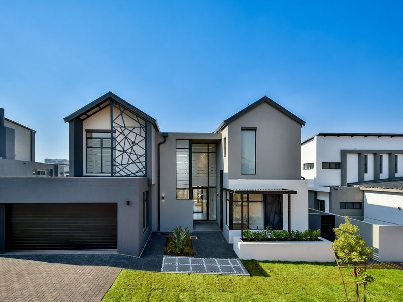Modern double-story residential home featuring a contemporary facade, integrated double garage, paved driveway, and manicured front garden.