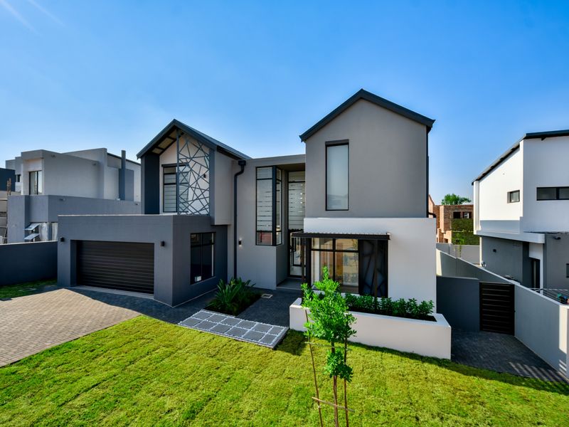 Modern double-story residential home featuring a contemporary facade, paved driveway, integrated double garage, and landscaped front garden.