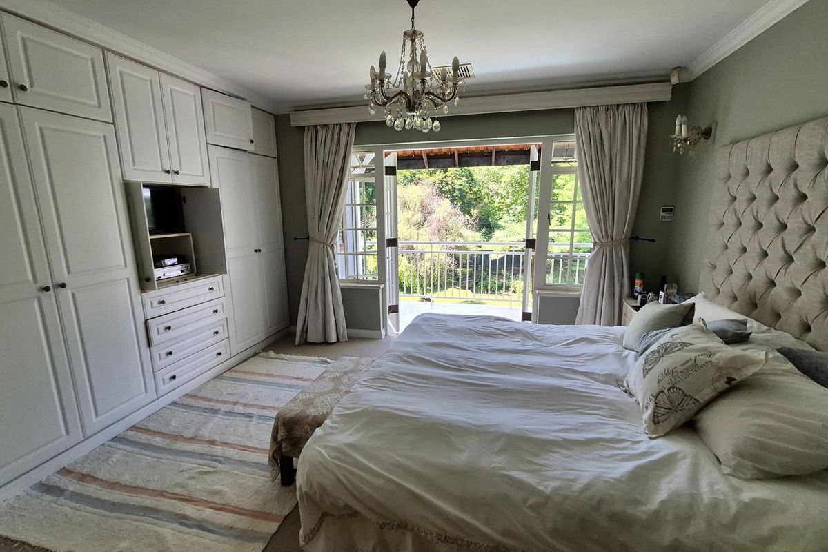 Spacious bedroom featuring extensive built-in cabinetry, elegant crown molding, and direct access to a private balcony through classic french doors.