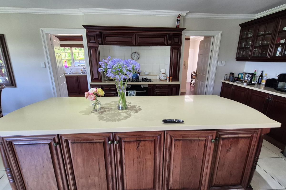 Spacious kitchen featuring a large central island, traditional dark wood cabinetry, built-in cooking appliances, and tiled flooring.