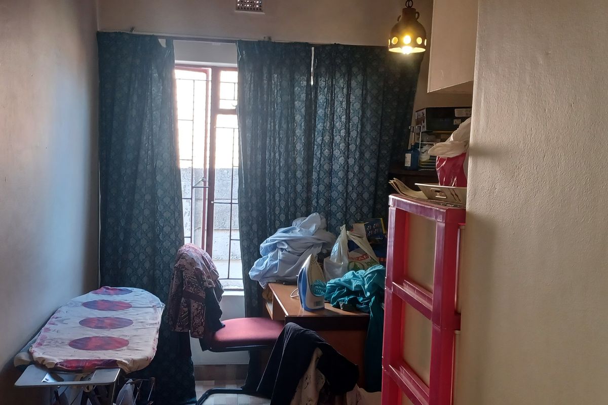 A small bedroom or utility space featuring a window with security bars and basic lighting fixtures.
