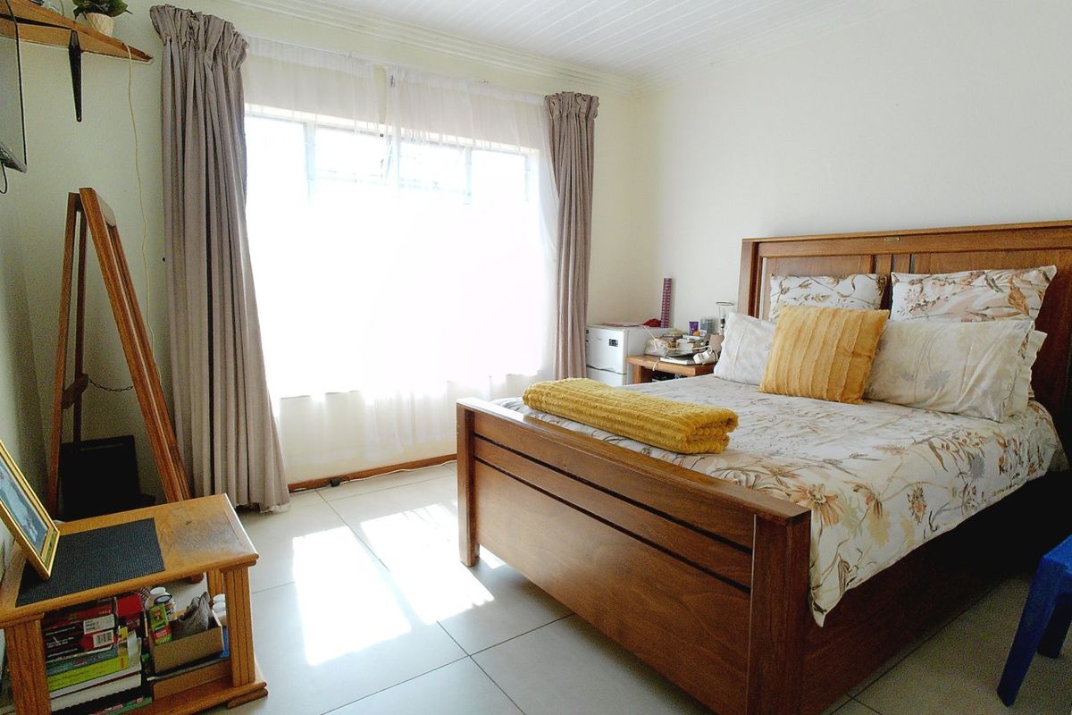 A well-lit bedroom featuring neutral tiled flooring and a timber-look ceiling, offering a comfortable and functional living space.