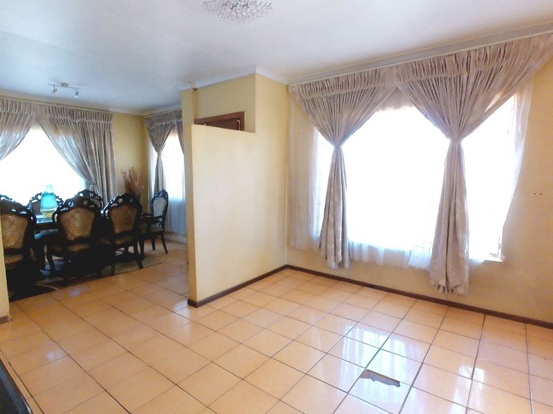 Open plan living and dining area featuring tiled flooring and a central partition wall, offering a versatile layout for family living.