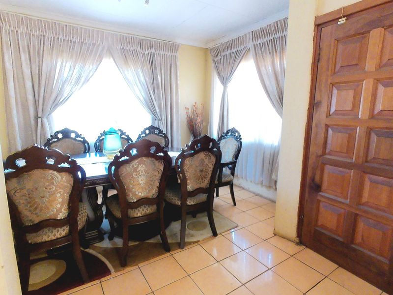 A dining room featuring ceramic tile flooring and a solid wood panel door, offering a functional space for family meals.
