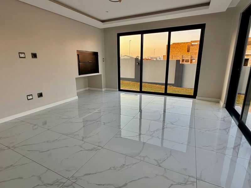 Modern, spacious living area featuring large format marble-look porcelain tiles, recessed ceiling detail, and sliding glass doors opening to the rear garden.