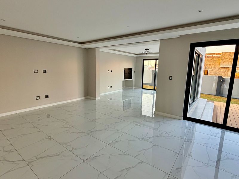 Spacious open-plan living area featuring polished porcelain tile flooring, recessed ceiling lighting, and large sliding glass doors leading to an outdoor deck and pool.