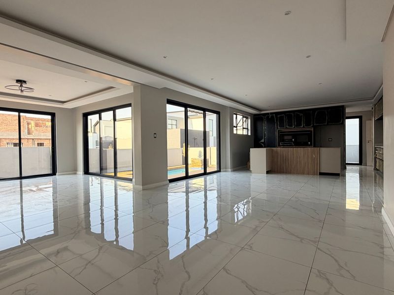 Spacious open-plan living and kitchen area featuring large sliding glass doors, polished porcelain tiles, and a modern kitchen layout currently undergoing final finishing touches.