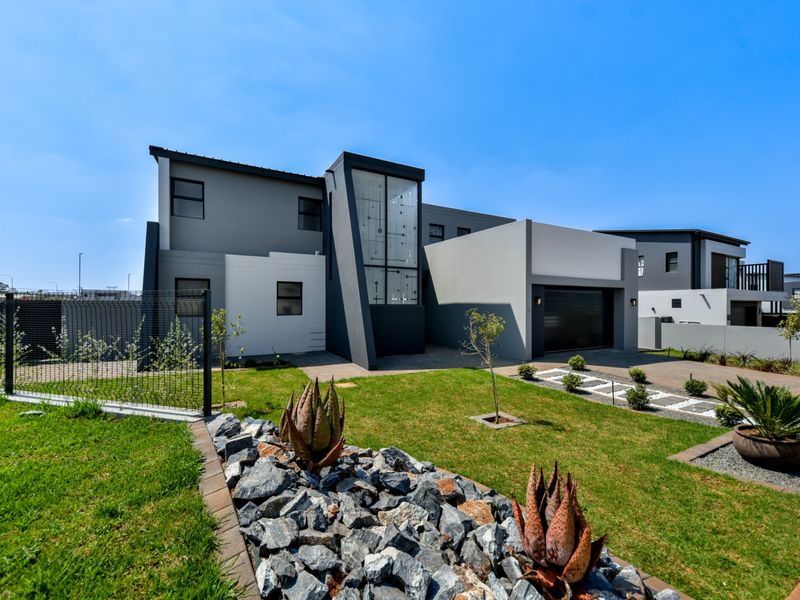 Modern double-story residential home featuring a contemporary facade, paved driveway, double garage, and well-maintained landscaped front garden.