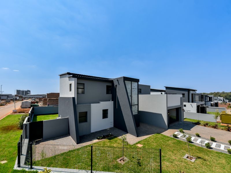A modern two-story residential property featuring a contemporary facade, paved driveway, integrated garage, and well-maintained garden in a suburban estate setting.