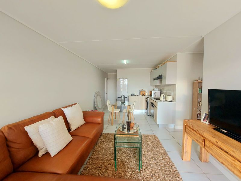 An open-plan living and kitchen area featuring tiled flooring, modern cabinetry, and a functional layout suitable for comfortable apartment living.