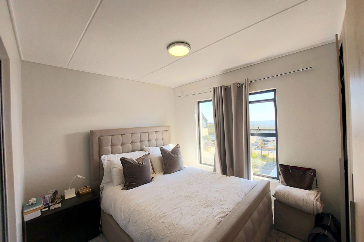 A well-lit bedroom featuring tiled flooring, a built-in cupboard, and a window with natural light, providing a comfortable and functional living space.