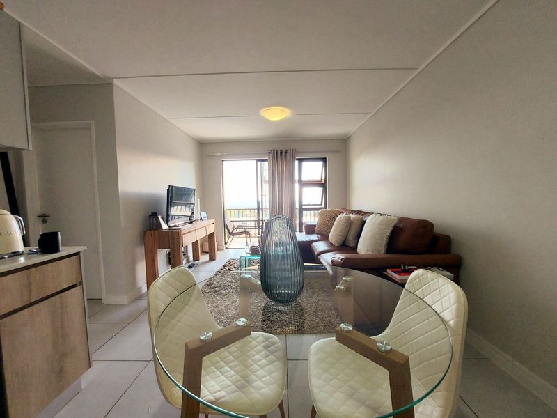 An open-plan living and dining area featuring tiled flooring and a sliding glass door leading to an outdoor balcony.