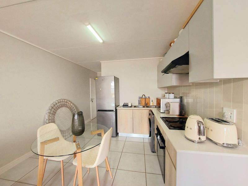 A functional kitchen featuring built-in cabinetry, a ceramic hob, an integrated oven, and a tiled backsplash, with an adjacent dining area.