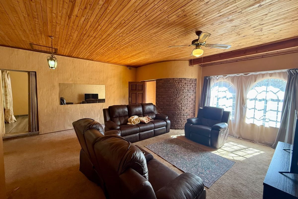 Spacious living room featuring a warm timber-clad ceiling, exposed brick accent wall, and large arched windows that provide ample natural light.