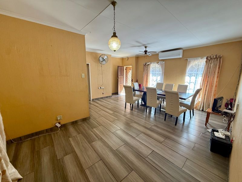 Spacious dining area featuring wood-look tile flooring, a split-system air conditioner, and a ceiling fan, offering a functional space for family meals.