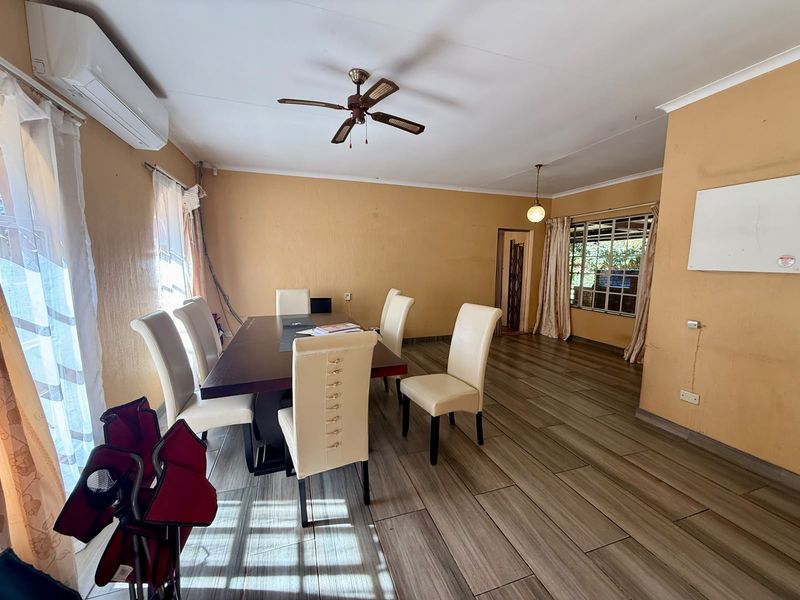 Spacious dining area featuring wood-look tiled flooring, a ceiling fan, and a wall-mounted air conditioning unit.