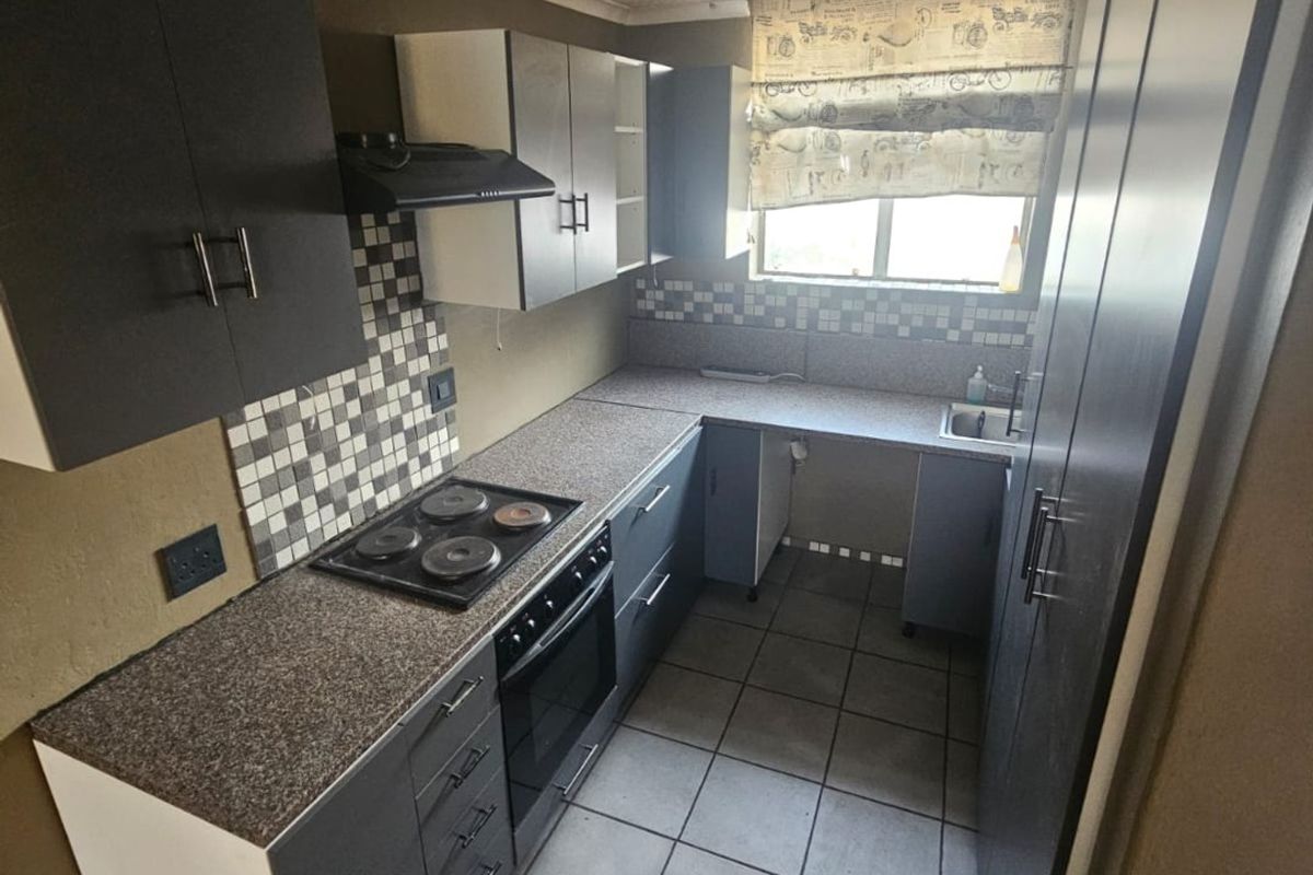 A compact kitchen featuring dark cabinetry, a built-in oven and hob, mosaic tile backsplash, and tiled flooring, offering a functional layout for renovation.