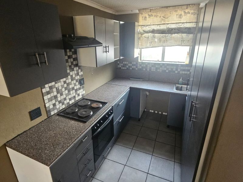 A compact kitchen featuring dark cabinetry, a built-in oven and hob, mosaic tile backsplash, and tiled flooring, offering a functional layout for renovation.