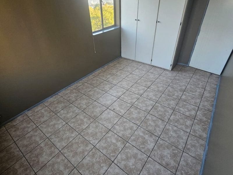 An empty bedroom featuring tiled flooring and built-in cupboards, offering a neutral space ready for personalization.