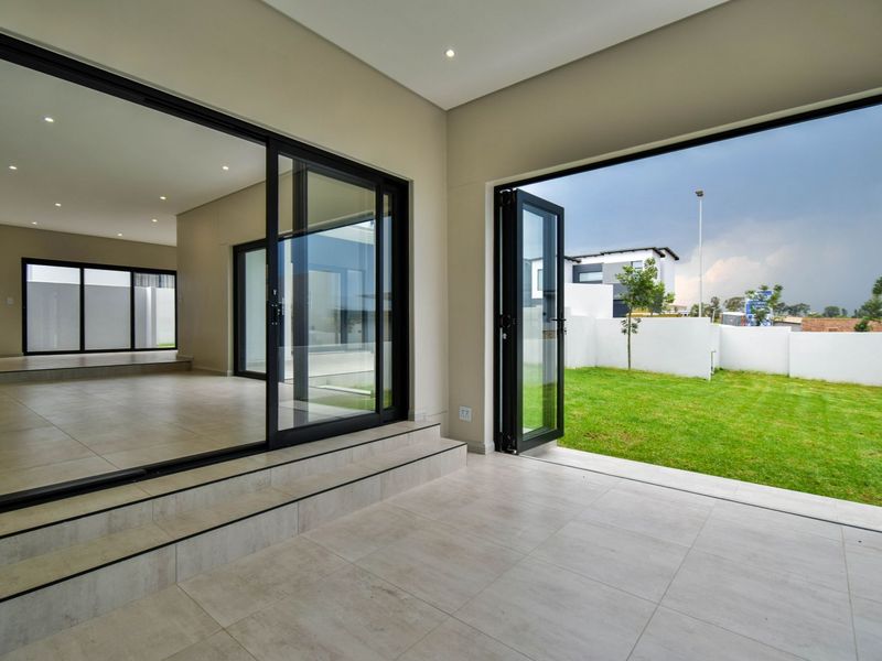 Spacious open-plan living area featuring modern tiled floors, recessed lighting, and seamless indoor-outdoor flow through large sliding and bi-fold glass doors to the garden.