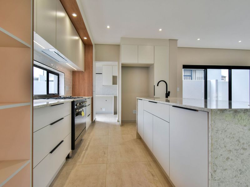 Modern kitchen featuring a stone island, built-in oven, gas hob, and sleek cabinetry, offering a clean and functional space for culinary activities.