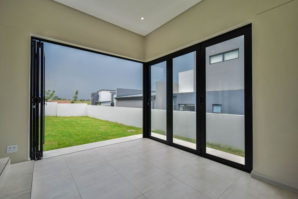 A bright, modern living space featuring large black-framed bi-fold doors that open directly onto a private garden area.
