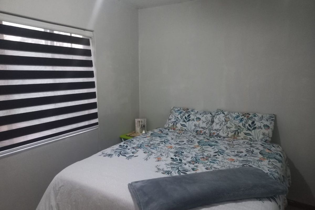 A simple bedroom featuring neutral walls and modern zebra-style window blinds.