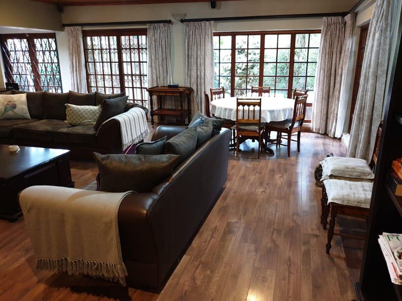 Spacious open-plan living and dining area featuring wood-look laminate flooring and large timber-framed glass doors providing access to the garden.