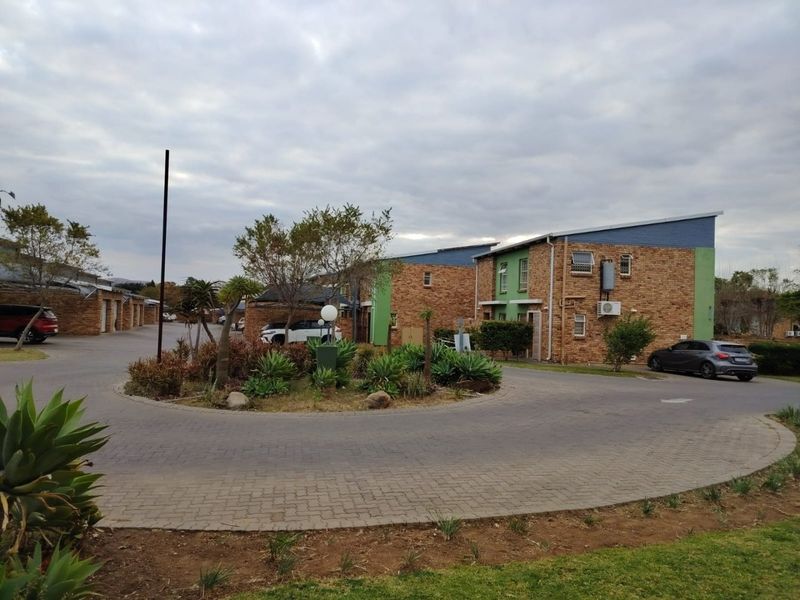 Exterior view of a residential apartment complex featuring brick facades, paved driveway, and established garden landscaping in a communal setting.