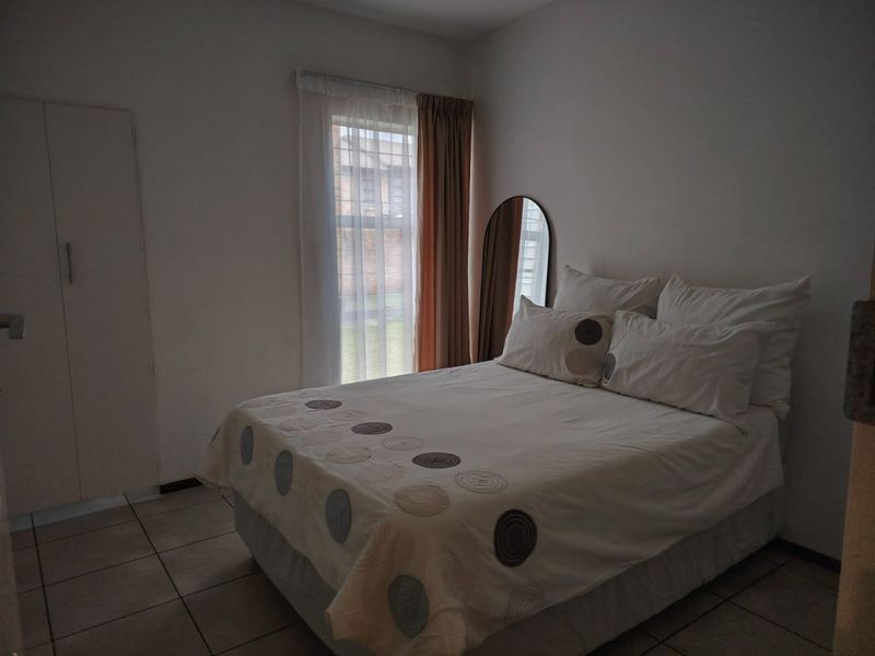 A functional bedroom featuring tiled flooring and a built-in cupboard, providing essential storage space within the apartment.