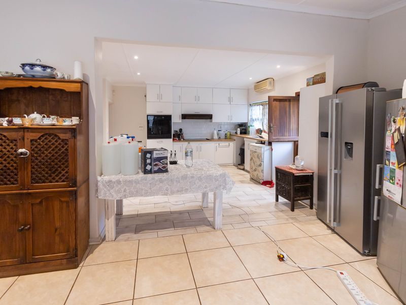 Open-plan kitchen and dining area featuring tiled flooring, white cabinetry, built-in oven, and recessed lighting, providing a functional space for cooking and dining.