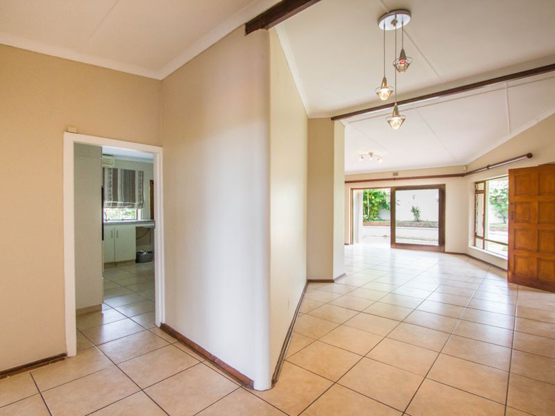 Spacious open-plan living area featuring tiled flooring, vaulted ceilings, and large sliding glass doors providing access to the exterior.
