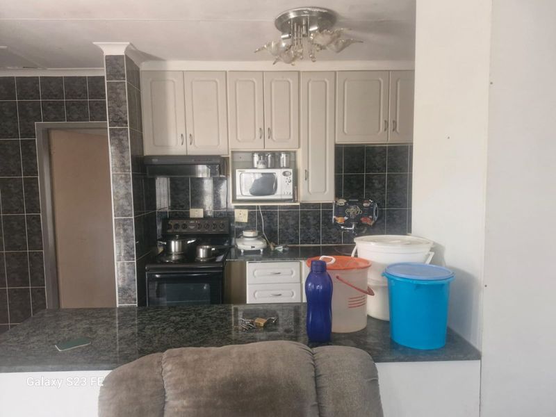 A functional kitchen featuring built-in cabinetry, granite countertops, a tiled backsplash, and integrated appliances including a stove and extractor fan.