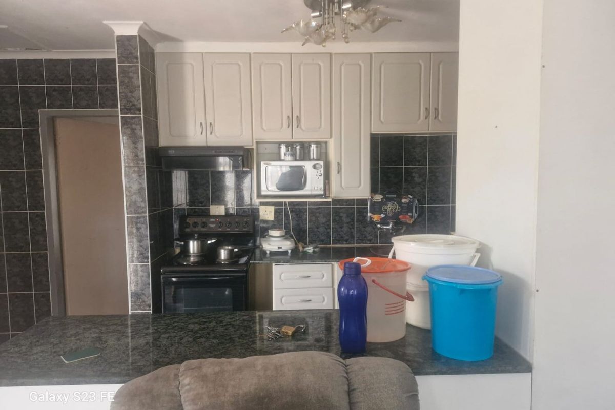 A functional kitchen featuring built-in cabinetry, granite countertops, a tiled backsplash, and integrated appliances including a stove and extractor fan.
