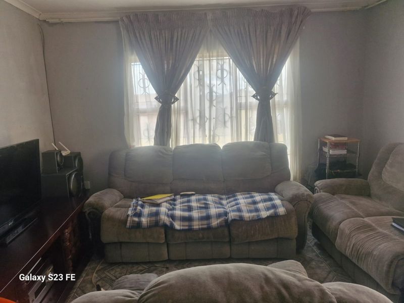 A living room area featuring tiled flooring and window treatments, offering a functional space ready for cosmetic updates and modernization.