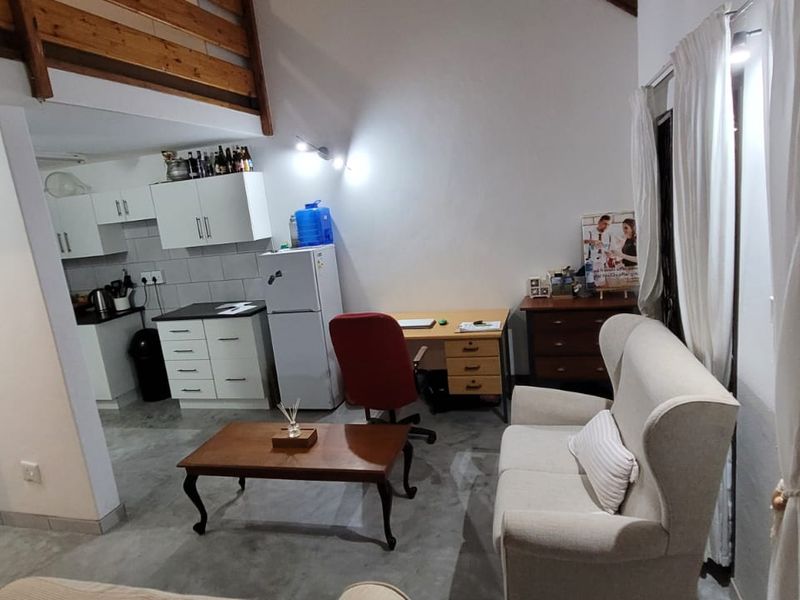 Open-plan living area featuring a functional kitchen with built-in cabinetry, concrete flooring, and a mezzanine level, creating a versatile and spacious living environment.