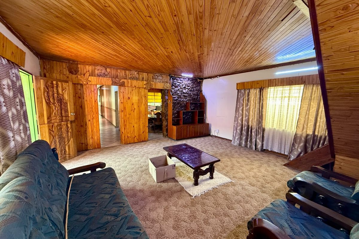Spacious living room featuring a vaulted timber-clad ceiling, stone-clad feature wall, and extensive timber paneling throughout.